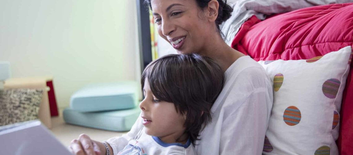Smiling mother reading a book to her son at bedtime